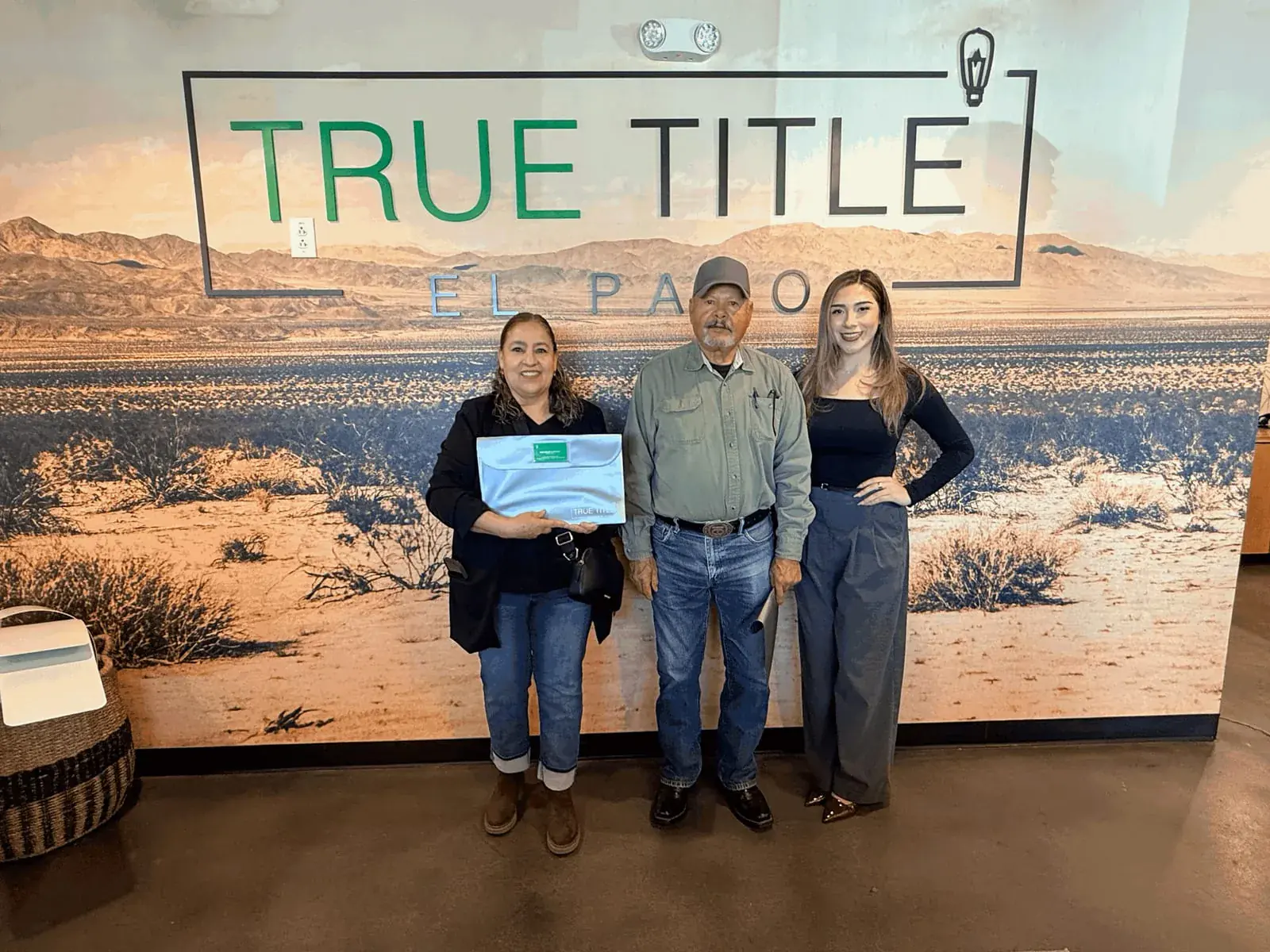 Ximena Martinez with two clients holding their closing folder on closing day